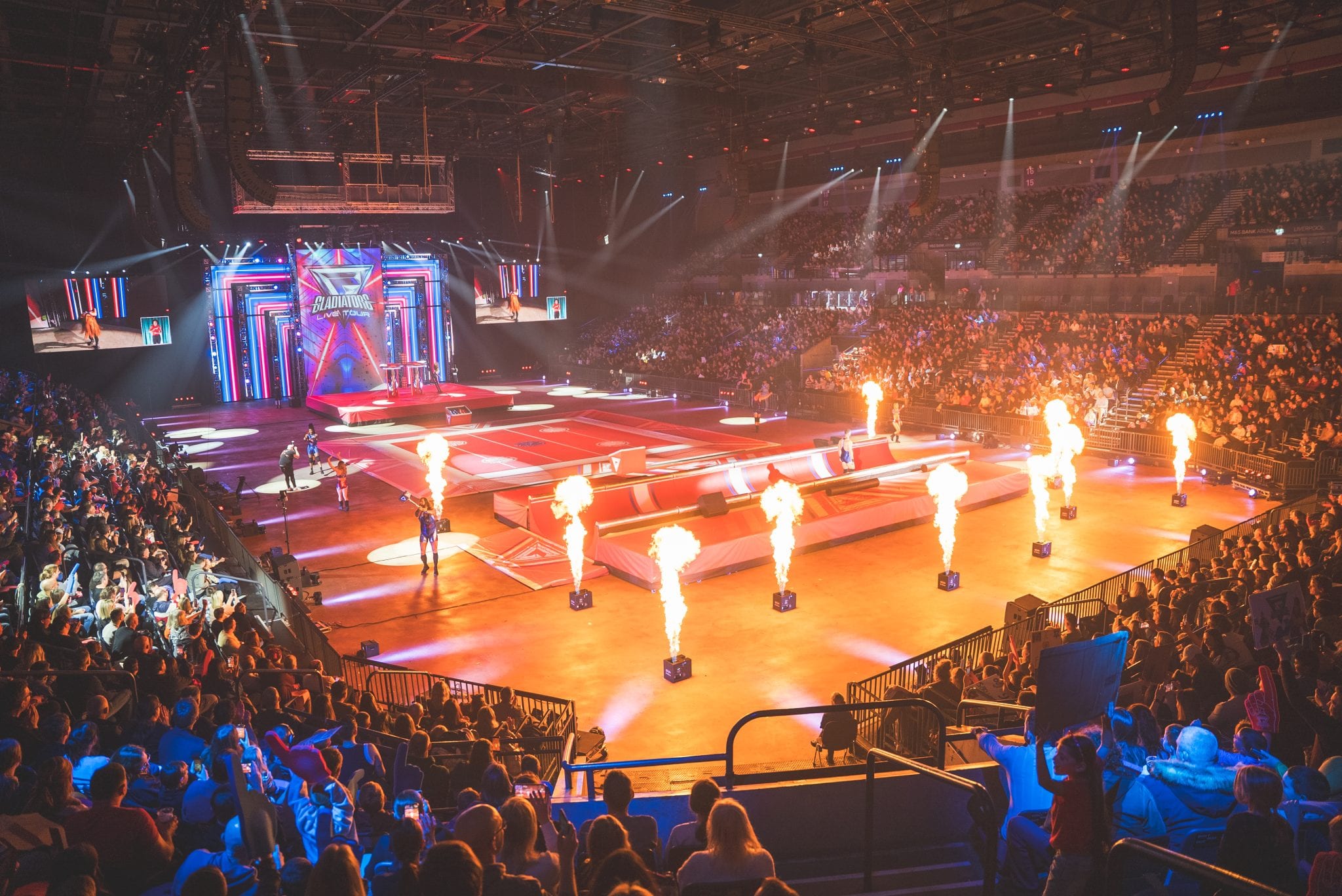 Arena-wide view of Gladiators Live Tour 2025: LED screens, lighting rig, flame jets and a full house.